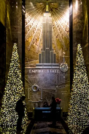 The lobby of the Empire State Building glowing with elegant holiday lights and festive decor.
