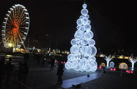 A beautifully lit street in Paris with a glowing Ferris wheel and dazzling Christmas decorations.